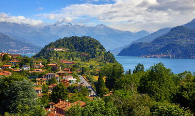 Bellagio village at lake Como, Italy. Panoramic view at hill with park and antique city among mountains and green forests. Summer picturesque landscape with water, waves and blue sky with clouds.