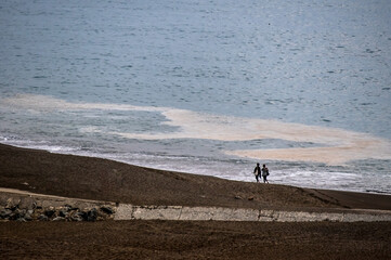 Fototapeta na wymiar COUPLE WALK ON BEACH ON COOL NORTHERN CALIFORNIA DAY.