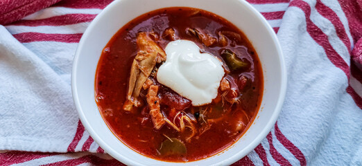 Soljanka in einer weißen Schale mit saurer Sahne auf einem Küchentuch