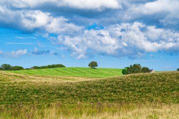 Paysage de prairies et de champs sous un ciel bleu avec quelques nuages à proximité du lac Chauvet en Auvergne (commune de Picherande) en juillet 2021