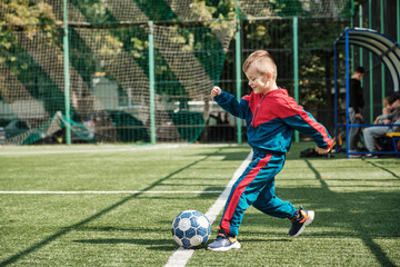 Schoolboy playing football on the Playground. Moment of hitting the ball.