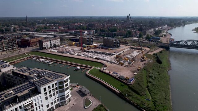 Backwards descending aerial movement showing outline view of luxury apartment Kade Zuid complex construction site revealing newly build Noord in the foreground on the other side of recreational port