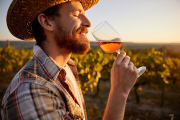 Happy winemaker tasting wine in vineyard