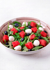 Salad with watermelon, arugula, blueberry, mozzarella and pine nuts in the bowl. Healthy meal