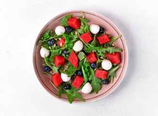 Salad with watermelon, arugula, blueberry, mozzarella and pine nuts in the bowl. Healthy meal. Top view