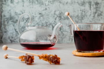 a sugar lollipop lies next to a mug and a teapot with karkade