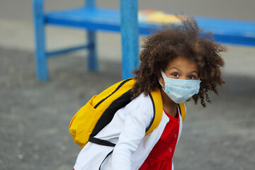 Portrait of a Black schoolgirl in a medical disposable mask after school on the playground