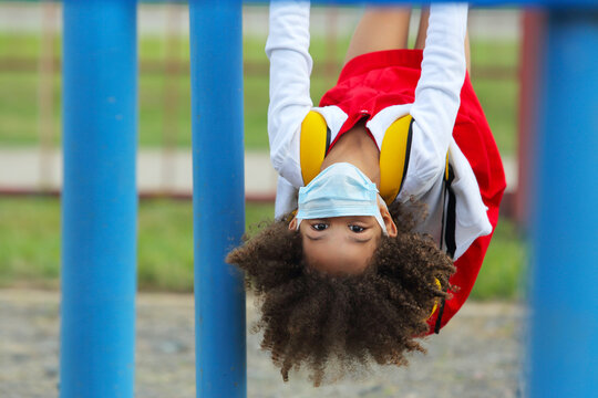 Portrait Of A Black Schoolgirl In A Medical Disposable Mask After School On Gym Equipment