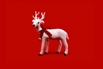 White toy reindeer on Christmas red background. Merry Christmas and Happy New Year seasons greetings concept. Edgeless centered minimal.