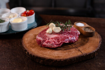 Wagyu chuck steak on a wooden cutting board Garnish with rosemary and garlic.