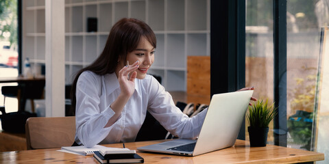 Cheerful young asian woman using laptop computer at home. Student female in living room. online learning, studying , online shopping, freelance, asean concept