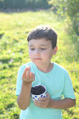niño feliz con una taza llena de moras al atardecer - 455137599