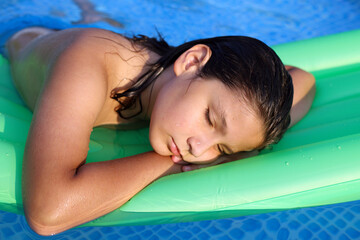 niño durmiendo en una colchoneta en la piscina - 455137989