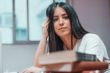 Obraz premium Chica joven adolescente de pelo castaño estudiando para el examen en la biblioteca del campus universitario con libros y ordenador portatil laptop