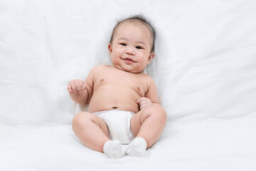 portrait of a smile cute little baby boy in diaper sitting on white sofa.The care for the baby.