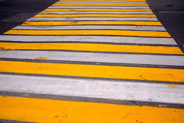 road marking pedestrian crossing on cracked asphalt, abstract background. White and yellow pedestrian crossing. Modern yellow and white zebra crossing..