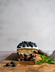 Blueberry cake with cream cheese ganache on the wooden board on the grey background