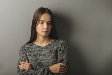 teenager abuse,sad depressed teen girl stands with her arms crossed, looking down © yta