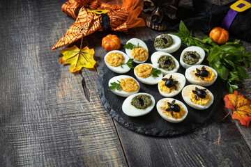 Halloween funny idea for party food. Halloween creative set stuffed eggs on a wooden table. Copy space.