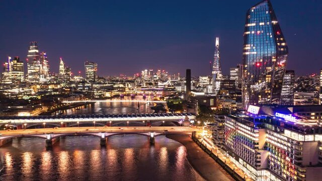 Aerial night hyperlapse footage of city. Forwards fly above Thames river at Blackfriars Bridge. Scene illuminated by city lights. London, UK