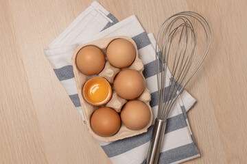 Whisk or egg beater with brown chicken eggs in a eco basket. Fresh egg on morning breakfast, flat lay, copy space.
