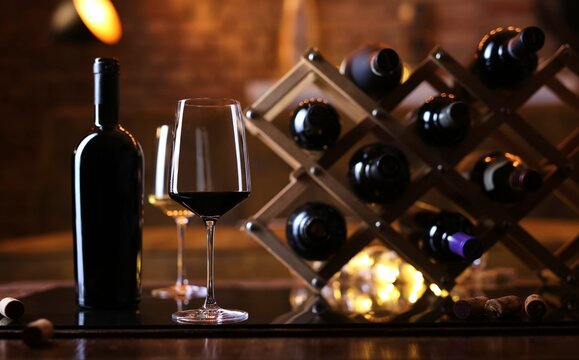 Glasses of red and white wine on table with wine bottle holder.