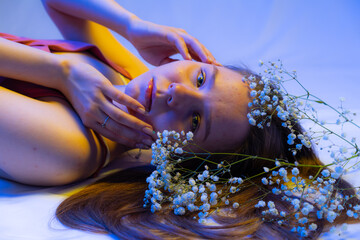 portrait of a girl with white flowers. multicolored light on background and face