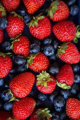 Background of assorted fresh berries of red juicy strawberries and blue blueberries close-up. View...