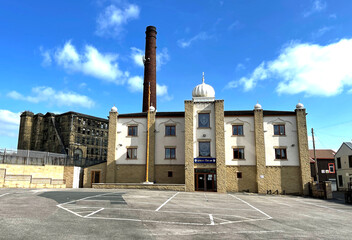 Sikh Temple, with a derelict Victorian stone built mill, and brick chimney in the background on,...