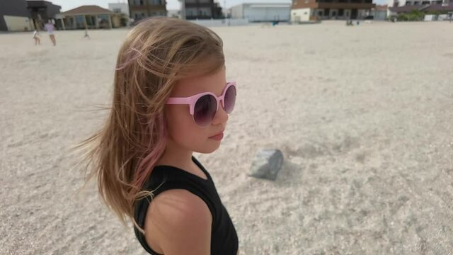 close up portrait girl looking serious contemplative kid on sunny seaside beach real people series