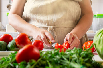 Chef slicing tomato using knife on the table in restaurant. Process of cutting and preparation food in kitchen.