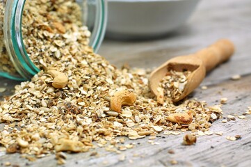 Homemade granola in white bowl with cashew nuts and seeds on grey background