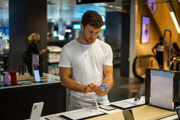 Focused man choosing smartphone in electronics store