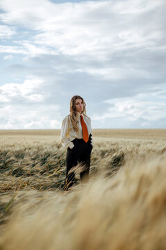 Stylish thoughtful model in wheat field under cloudy sky