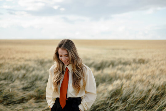 Stylish happy woman laughing in wheat field under cloudy sky
