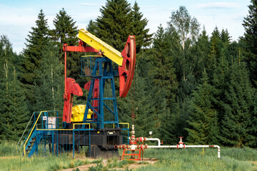 oil pumping station with pumpjack in a clearing in the forest