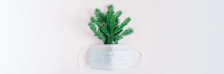spruce branches and a medical face mask. concept of coronavirus covid 19 infection and the onset of the new year, the need to continue to yourself protect. flat lay, space for text. banner