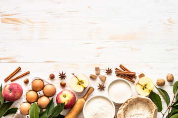 Ingredients for cooking autumn baking. Flour, sugar, eggs, apples and spices at white wooden table. Top view with space for design.