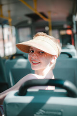 a girl with short hair, in a baseball cap, in a dress, is riding alone on a bus, a beautiful girl with short hair, wearing a hat on the bus smiles