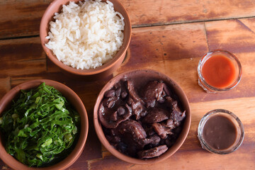 typical Brazilian food feijoada made with beans, pork, bacon, sausage with cabbage, rice, salad, spices and pepper.