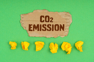 On a green background, crumpled yellow paper and a cardboard with the inscription - co2 emission