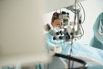 Ophthalmologist looking through microscope during eye operation in clinic
