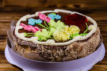 Kiev cake with cream, nuts and meringue in cardboard box on a wooden table