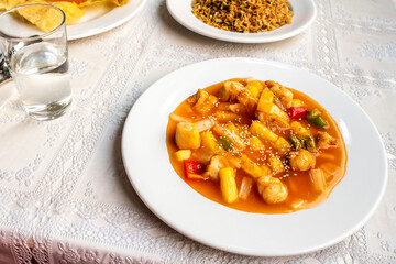 chinese recipe for chicken with pineapple and vegetables sautéed with sauce and sesame seeds with onions on white tablecloth in chinese restaurant