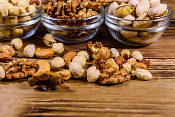 Various nuts (almond, cashew, hazelnut, pistachio, walnut) in glass bowls on a wooden table. Vegetarian meal. Healthy eating concept