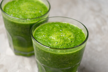 Green juice in glass on grey background
