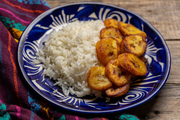 Rice and fried banana also called cuban style on wooden background
