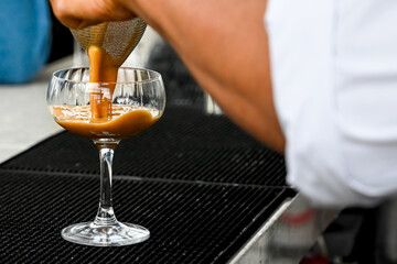 Barperson pouring an espresso martini cocktail into a couple glass.