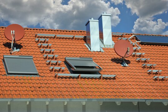 Technische Anlagen auf einem Wohngebäude: Satelliten-Antenne, Edelstahl-Schornstein mit Abspannung, Solaranlage, Gaube, Dachfenster, Regenrinne, Metall-Dachverkleidung