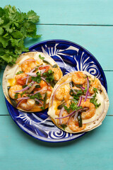 Mexican food. Shrimp tacos with melted cheese and poblano pepper called gobernador on turquoise background.